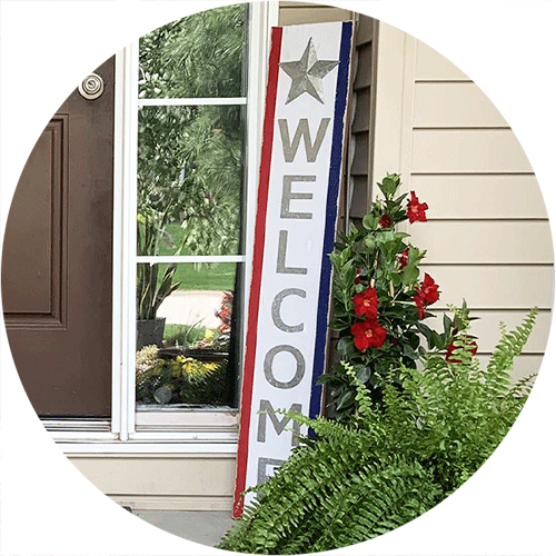 A red, white and blue, tall, wooden Welcome sign.